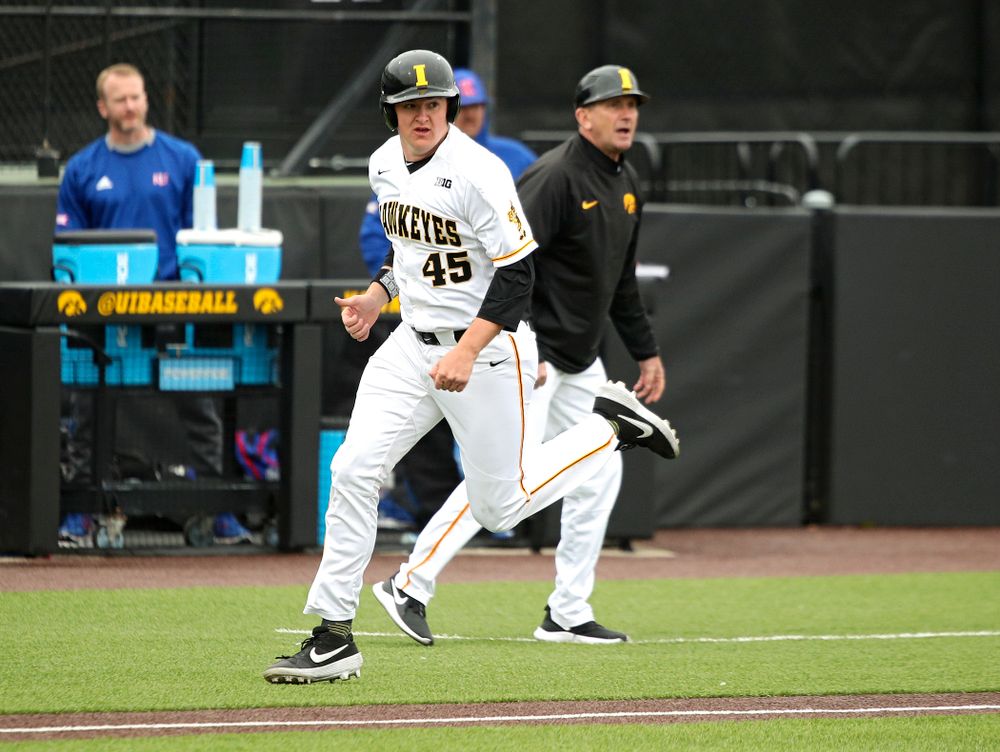 Iowa first baseman Peyton Williams (45) runs past head coach Rick Heller as he scores a run during the first inning of their college baseball game at Duane Banks Field in Iowa City on Wednesday, March 11, 2020. (Stephen Mally/hawkeyesports.com)