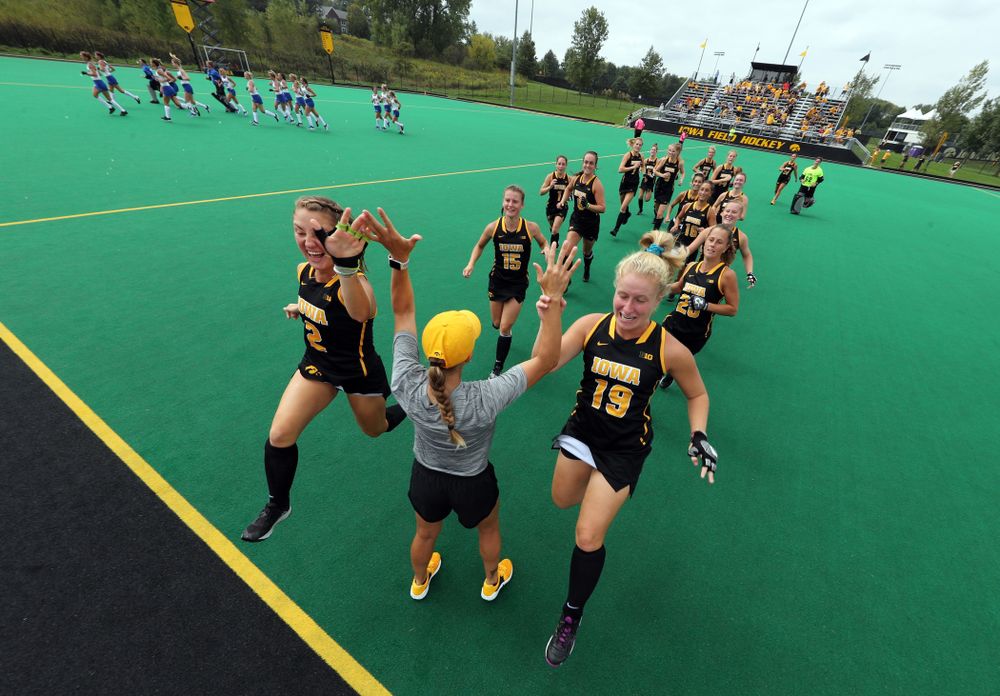 Iowa Hawkeyes defenseman Emily Deuell (2) and forward Ryley Miller (19) slap hands with assistant coach Roz Ellis before their game against the Duke Blue Devils Sunday, September 15, 2019 at Grant Field.  (Brian Ray/hawkeyesports.com)