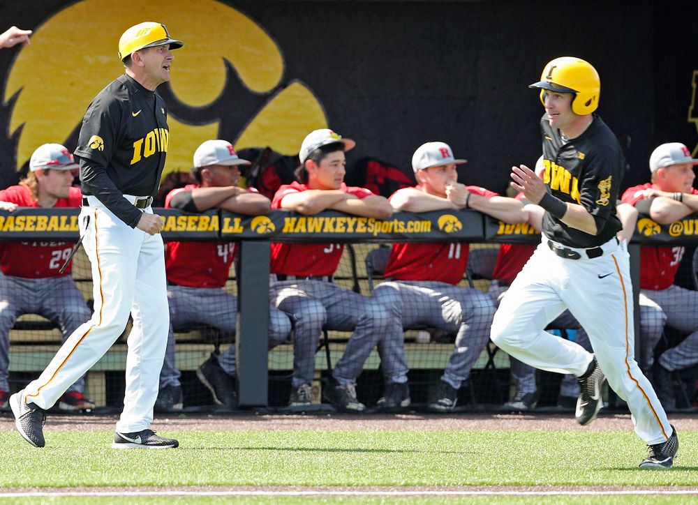 Iowa Hawkeyes head coach Rick Heller (from left) looks on as left fielder Chris Whelan (28) runs home to score a run during the first inning of their game against Rutgers at Duane Banks Field in Iowa City on Saturday, Apr. 6, 2019. (Stephen Mally/hawkeyesports.com)