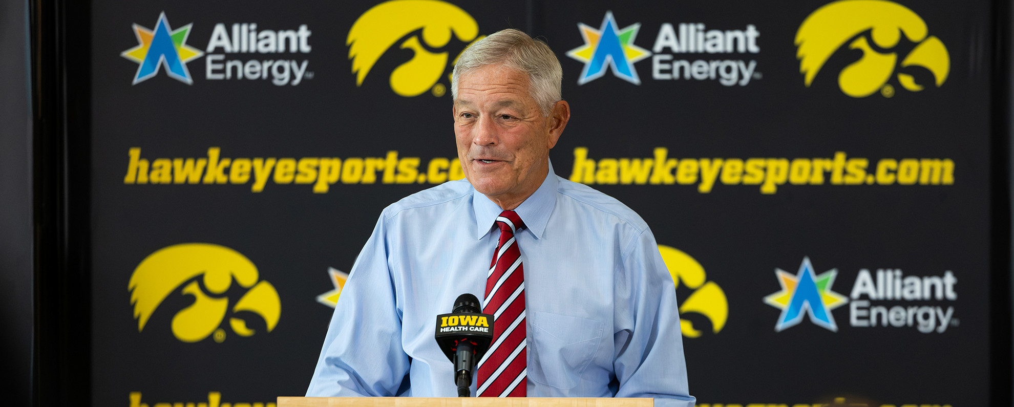 Kirk Ferentz speaks to reporters at the podium at a press conference.