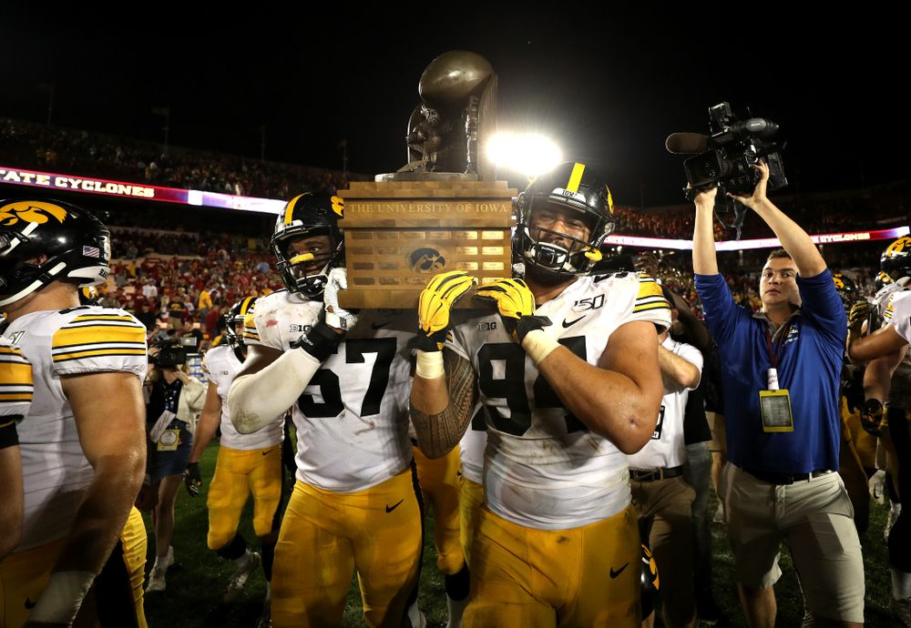 Iowa Hawkeyes defensive end Chauncey Golston (57) and defensive end A.J. Epenesa (94) celebrate with the Cy-Hawk trophy following their win over the Iowa State Cyclones Saturday, September 14, 2019 in Ames, Iowa. (Brian Ray/hawkeyesports.com)