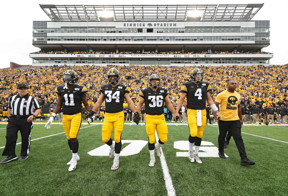 Iowa Hawkeyes captains defensive back Michael Ojemudia (11), linebacker Kristian Welch (34), fullback Brady Ross (36), and quarterback Nate Stanley (4) walk to the center of the field for the coin toss with honorary captain Miguel Merrick before their game at Kinnick Stadium in Iowa City on Saturday, Sep 28, 2019. (Stephen Mally/hawkeyesports.com)