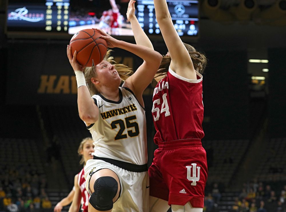 Iowa Hawkeyes forward Monika Czinano (25) scores a basket around the arms of Indiana Hoosiers forward Mackenzie Holmes (54) during the first quarter of their game at Carver-Hawkeye Arena in Iowa City on Sunday, January 12, 2020. (Stephen Mally/hawkeyesports.com)