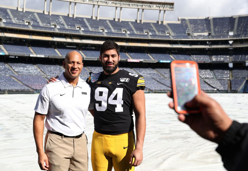 Iowa Hawkeyes special teams coordinator LeVar Woods  and defensive end A.J. Epenesa (94) following the team photo Wednesday, December 25, 2019 at SDCCU Stadium in San Diego. (Brian Ray/hawkeyesports.com)