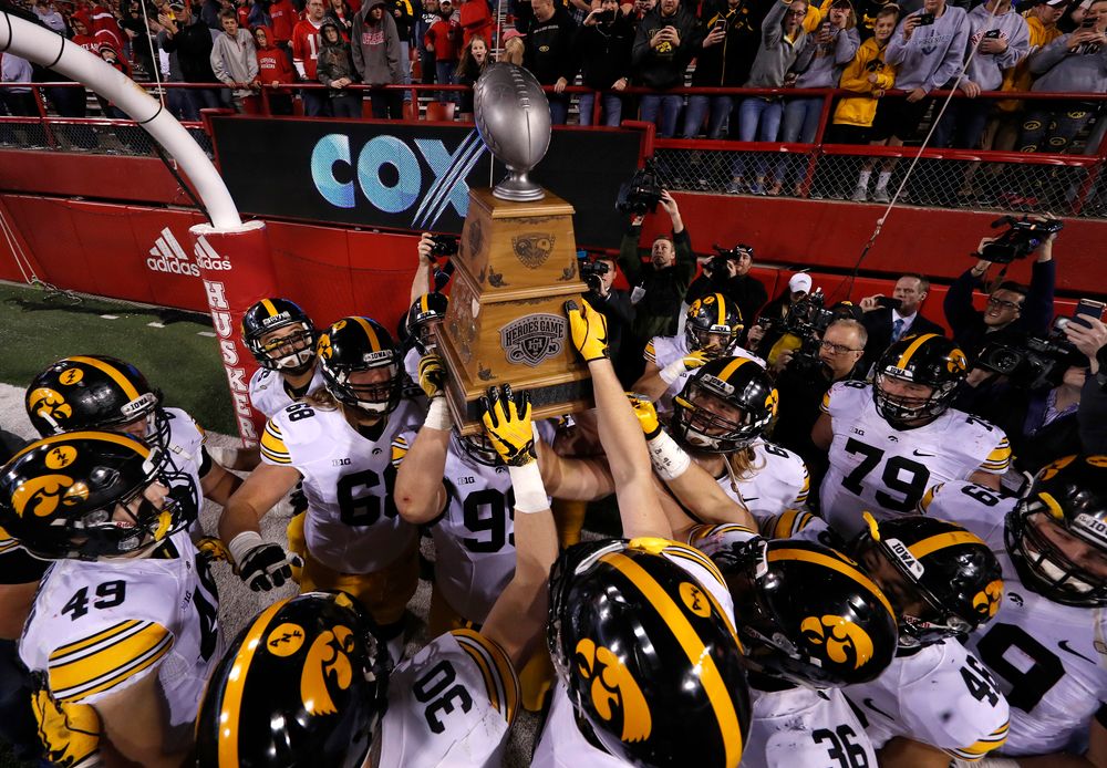 The Iowa Hawkeyes celebrate with the Heroes Game Trophy 