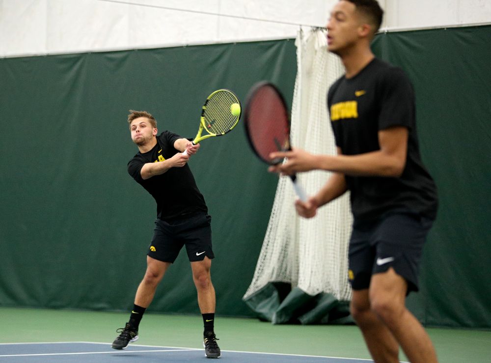 Iowa’s Will Davies (from left) returns a shot as Oliver Okonkwo looks on during their doubles match at the Hawkeye Tennis and Recreation Complex in Iowa City on Friday, February 14, 2020. (Stephen Mally/hawkeyesports.com)