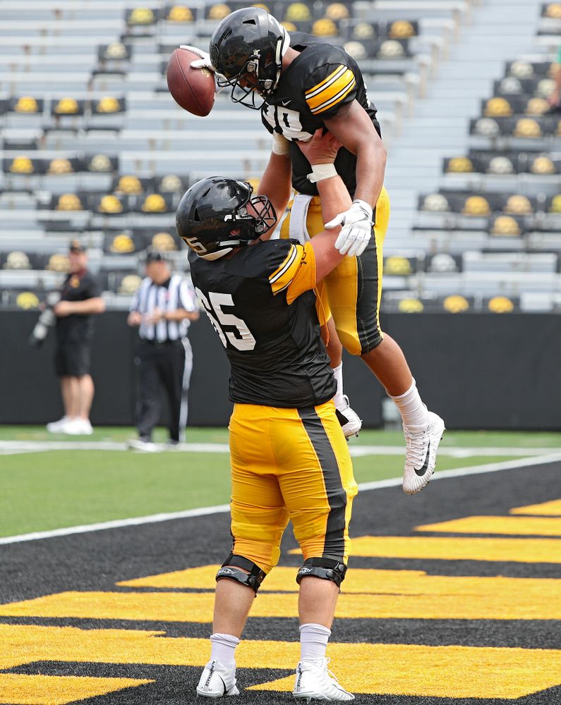 Iowa Hawkeyes offensive lineman Tyler Linderbaum (65) holds up running back Toren Young (28) after Young scored a touchdown during Fall Camp Practice No. 8 at Kids Day at Kinnick Stadium in Iowa City on Saturday, Aug 10, 2019. (Stephen Mally/hawkeyesports.com)