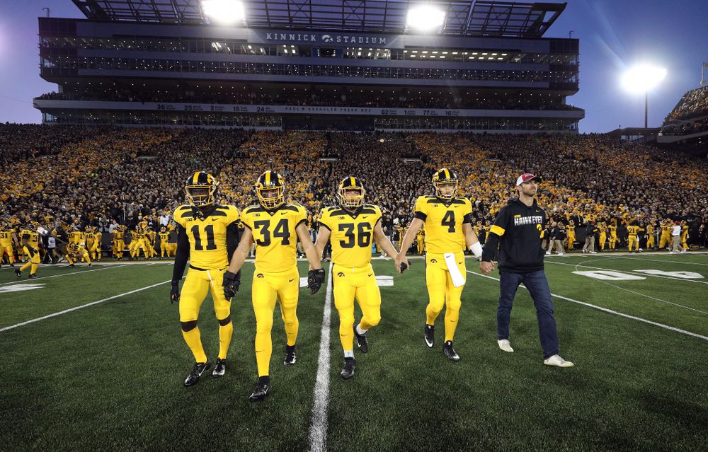 Iowa Hawkeyes captains defensive back Michael Ojemudia (11), linebacker Kristian Welch (34), fullback Brady Ross (36), and quarterback Nate Stanley (4), walk with honorary captain Ricky Stanzi before their game against the Penn State Nittany Lions Saturday, October 12, 2019 at Kinnick Stadium. (Brian Ray/hawkeyesports.com)