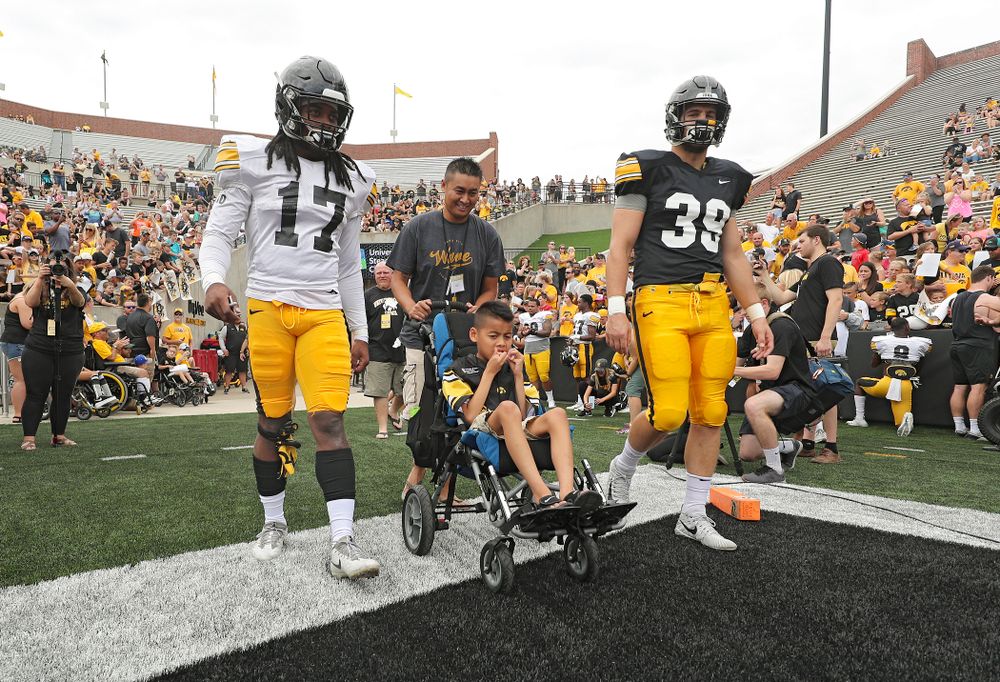 Iowa Hawkeyes defensive back Devonte Young (17) and tight end Nate Wieting (39) swarm with Kid Captain Enzo Thongsoum during Kids Day at Kinnick Stadium in Iowa City on Saturday, Aug 10, 2019. (Stephen Mally/hawkeyesports.com)