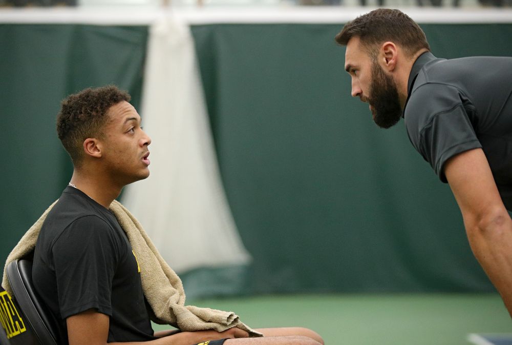 Iowa’s Oliver Okonkwo (from left) talks with assistant coach Lloyd Bruce-Burgess during his match against Marquette at the Hawkeye Tennis and Recreation Complex in Iowa City on Saturday, January 25, 2020. (Stephen Mally/hawkeyesports.com)