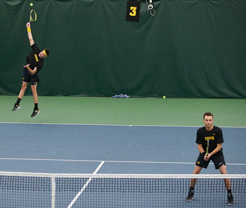 Iowa’s Nikita Snezhko (from left) serves as Kareem Allaf waits during their doubles match against Marquette at the Hawkeye Tennis and Recreation Complex in Iowa City on Saturday, January 25, 2020. (Stephen Mally/hawkeyesports.com)
