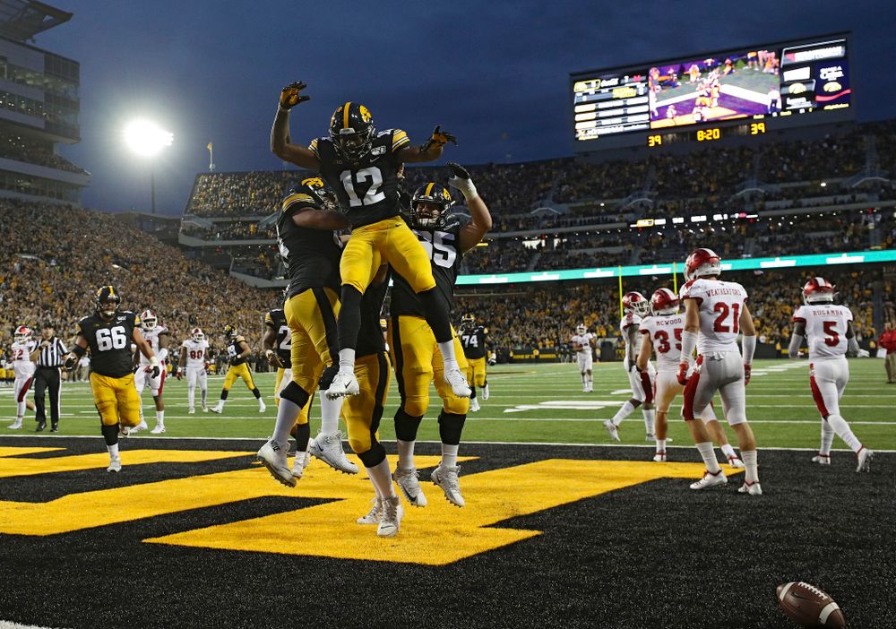Iowa Hawkeyes offensive lineman Kyler Schott (64), offensive lineman Landan Paulsen (68), and offensive lineman Tyler Linderbaum (65) celebrate with wide receiver Brandon Smith (12) after his 9-yard touchdown reception during the second quarter of their game at Kinnick Stadium in Iowa City on Saturday, Aug 31, 2019. (Stephen Mally/hawkeyesports.com)