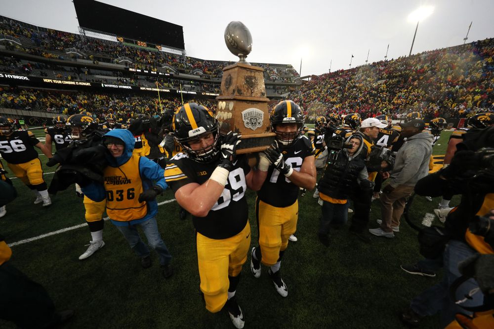Iowa Hawkeyes offensive lineman Keegan Render (69) and offensive lineman Dalton Ferguson (76)  carry the Heroes game trophy off the field following their win over the Nebraska Cornhuskers Friday, November 23, 2018 at Kinnick Stadium. (Brian Ray/hawkeyesports.com)