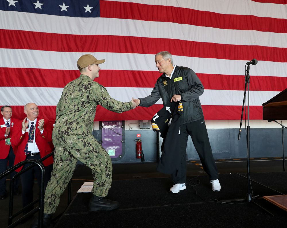 Iowa Hawkeyes head coach Kirk Ferentz presents a jersey to honorary captain Vincent OÕBrien of Bell Plaine during a tour of the USS Theodore Roosevelt (CVN-71) Tuesday, December 24, 2019 at the Naval Base Coronado. (Brian Ray/hawkeyesports.com)