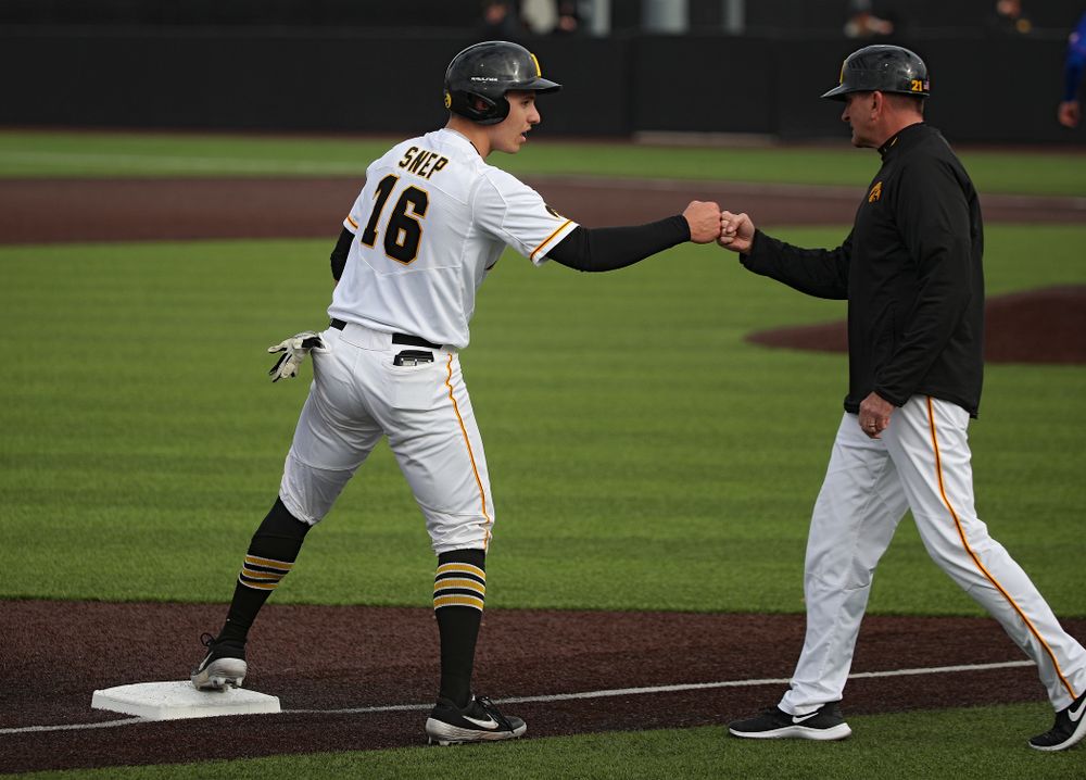 Iowa catcher Tyler Snep (16) gets a first bump from head coach Rick Heller after advancing to third on a wild pitch during the seventh inning of their college baseball game at Duane Banks Field in Iowa City on Wednesday, March 11, 2020. (Stephen Mally/hawkeyesports.com)