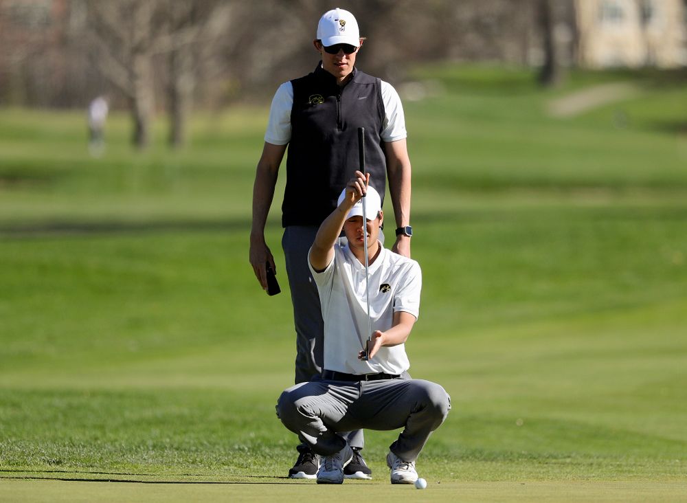 Iowa assistant coach Charlie Hoyle (top) stands above Joe Kim as he lines up a putt during the first round of the Hawkeye Invitational at Finkbine Golf Course in Iowa City on Saturday, Apr. 20, 2019. (Stephen Mally/hawkeyesports.com)