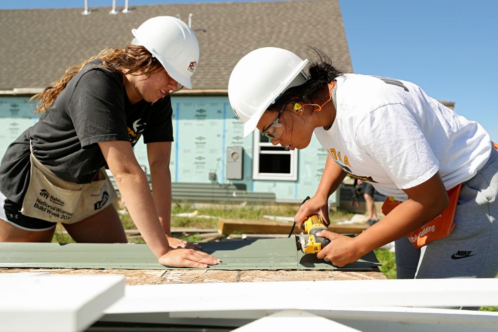 Iowa’s McKenna Warnock (from left) and Alexis Sevillian work on cutting a piece of siding as they work on a Habitat for Humanity Women Build project in Iowa City on Wednesday, Sep 25, 2019. (Stephen Mally/hawkeyesports.com)