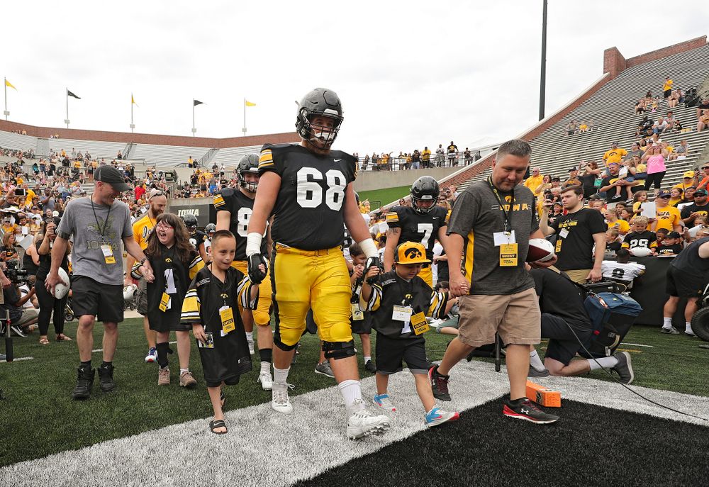 Kid Captains Lucy Roth, Skylar Hardee, and Jeg Weets lead the others as they swarm with Iowa Hawkeyes offensive lineman Landan Paulsen (68) during Kids Day at Kinnick Stadium in Iowa City on Saturday, Aug 10, 2019. (Stephen Mally/hawkeyesports.com)