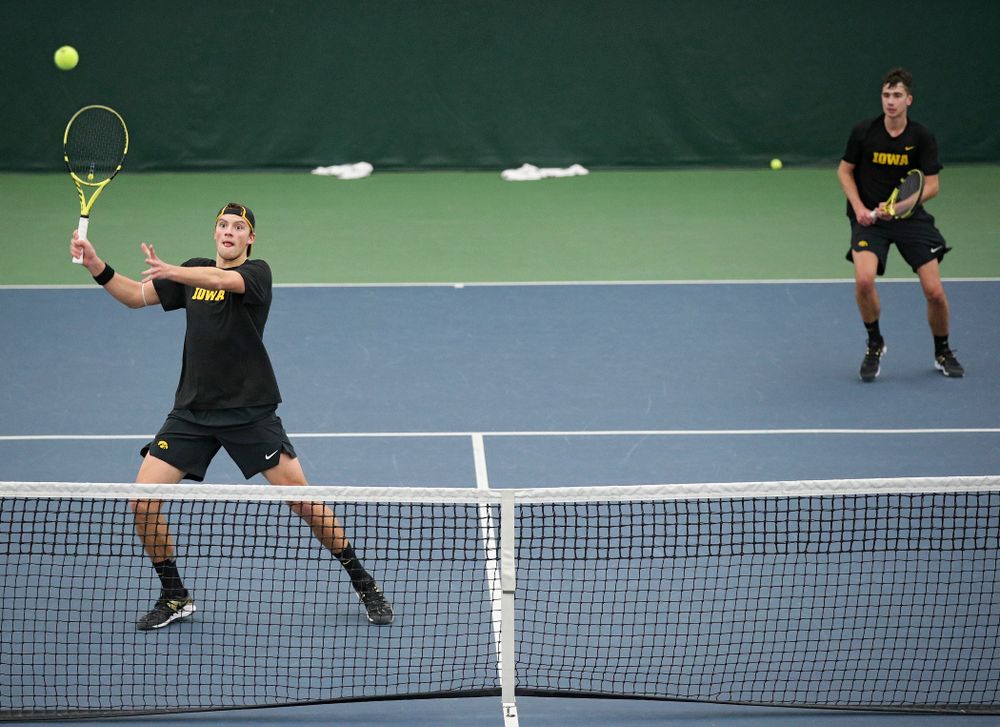 Iowa’s Joe Tyler (from left) hits a shot as Matt Clegg looks on during their doubles match against Marquette at the Hawkeye Tennis and Recreation Complex in Iowa City on Saturday, January 25, 2020. (Stephen Mally/hawkeyesports.com)
