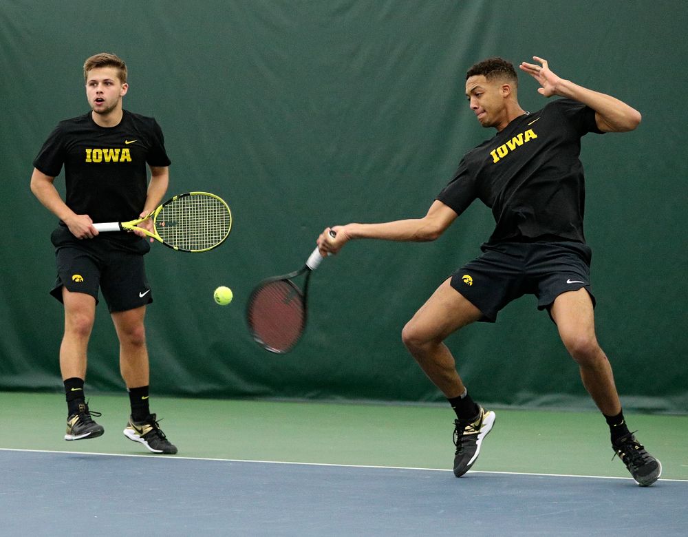 Iowa’s Oliver Okonkwo (right) returns a shot as Will Davies (left) looks on during their doubles match at the Hawkeye Tennis and Recreation Complex in Iowa City on Friday, February 14, 2020. (Stephen Mally/hawkeyesports.com)