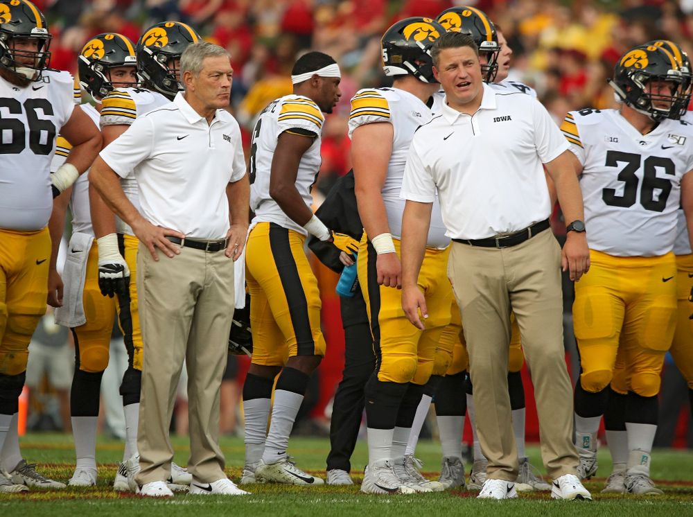 Iowa Hawkeyes head coach Kirk Ferentz (from left) talks with offensive coordinator Brian Ferentz as the team warms up after a weather delay during the first quarter of their Iowa Corn Cy-Hawk Series game at Jack Trice Stadium in Ames on Saturday, Sep 14, 2019. (Stephen Mally/hawkeyesports.com)