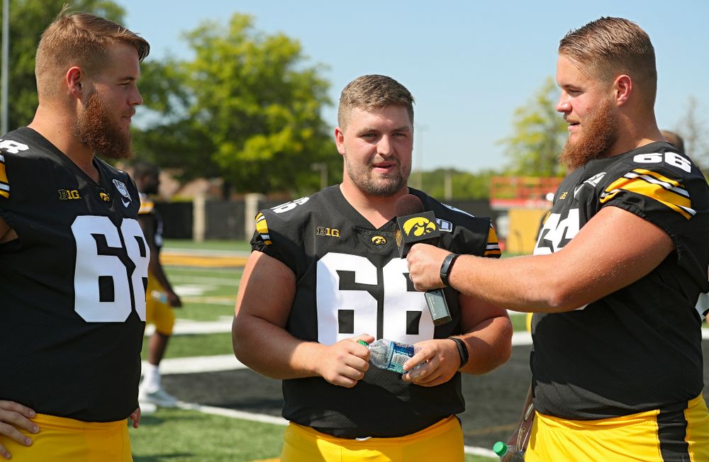 Iowa Hawkeyes offensive lineman Levi Paulsen (right) interviews defensive lineman Dalles Jacobus (center) as offensive lineman Landan Paulsen (68) looks on during Iowa Football Media Day at the Hansen Football Performance Center in Iowa City on Friday, Aug 9, 2019. (Stephen Mally/hawkeyesports.com)