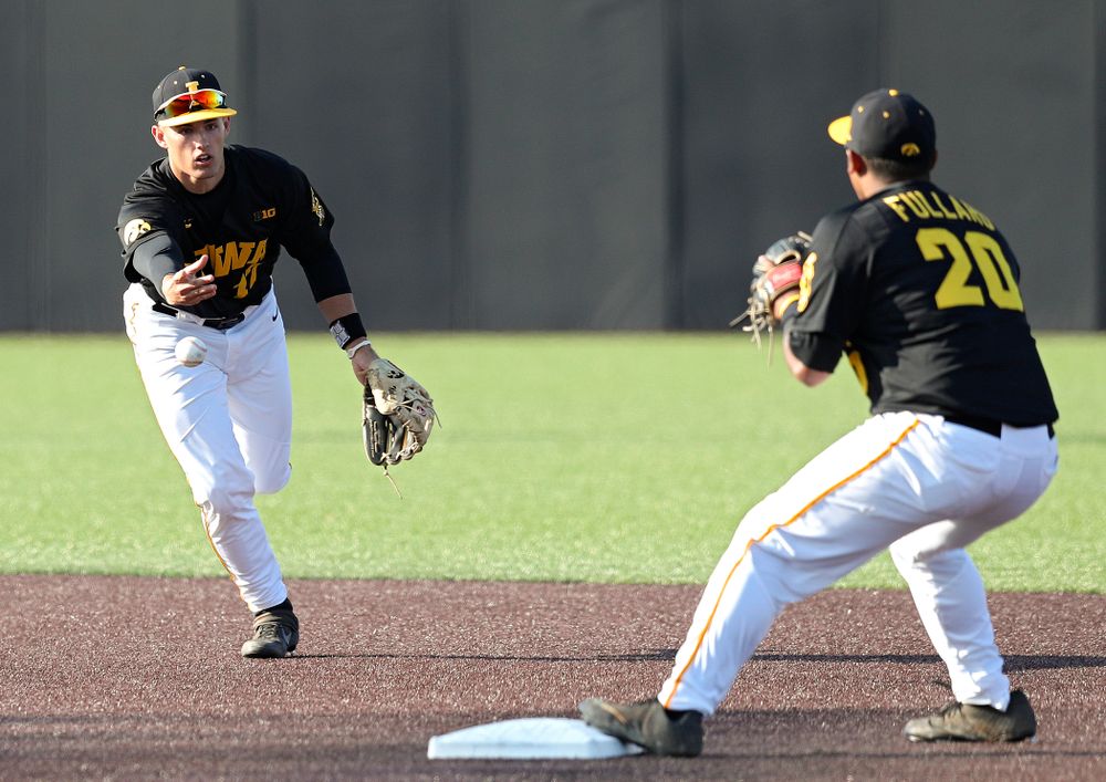 Iowa shortstop Dylan Nedved (from left) tosses the ball to infielder Izaya Fullard (20) as they turn a double play during the second inning of their college baseball game at Duane Banks Field in Iowa City on Tuesday, March 10, 2020. (Stephen Mally/hawkeyesports.com)