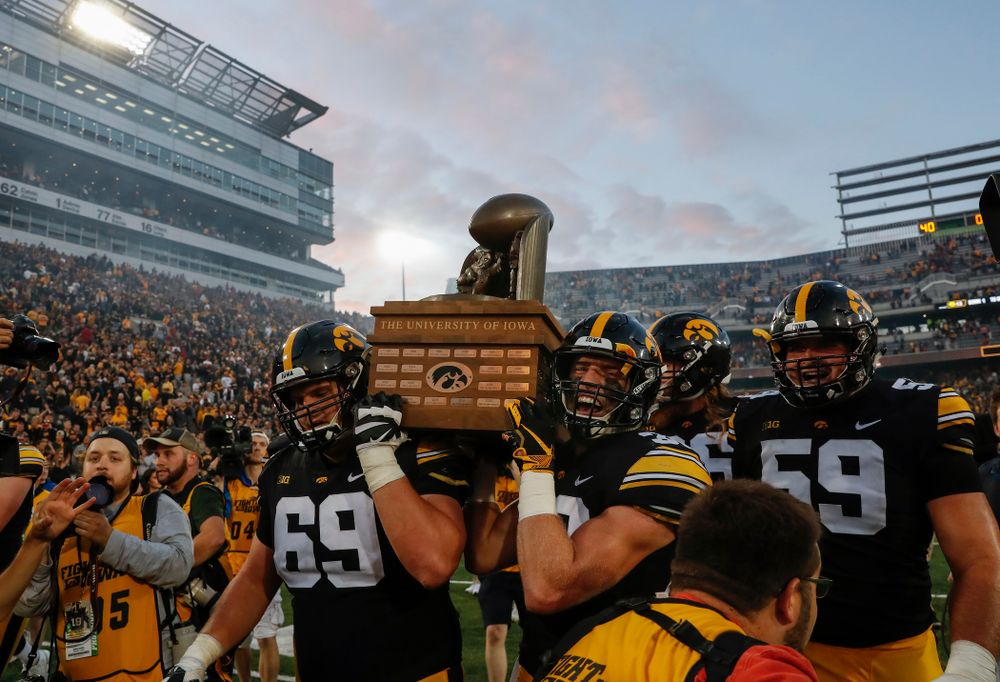 Iowa Hawkeyes offensive lineman Keegan Render (69) and defensive back Jake Gervase (30), offensive lineman Ross Reynolds (59) celebrate with the Cy-Hawk trophy following their game against the Iowa State Cyclones Saturday, September 8, 2018 at Kinnick Stadium. (Brian Ray/hawkeyesports.com)
