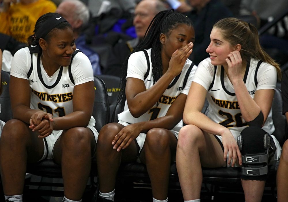 Iowa Hawkeyes guard Tomi Taiwo (1) whispers to guard Kate Martin (20) as she sits on the bench with guard Zion Sanders (21) during the fourth quarter of the game at Carver-Hawkeye Arena in Iowa City on Thursday, February 6, 2020. (Stephen Mally/hawkeyesports.com)