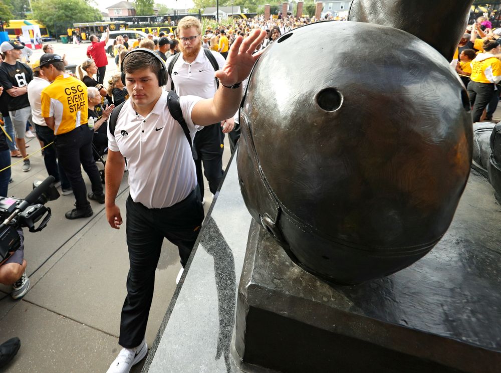 Iowa Hawkeyes offensive lineman Tyler Linderbaum (65) touches the helmet on the Nile Kinnick statue as the team arrives before their Big Ten Conference football game at Kinnick Stadium in Iowa City on Saturday, Sep 7, 2019. (Stephen Mally/hawkeyesports.com)