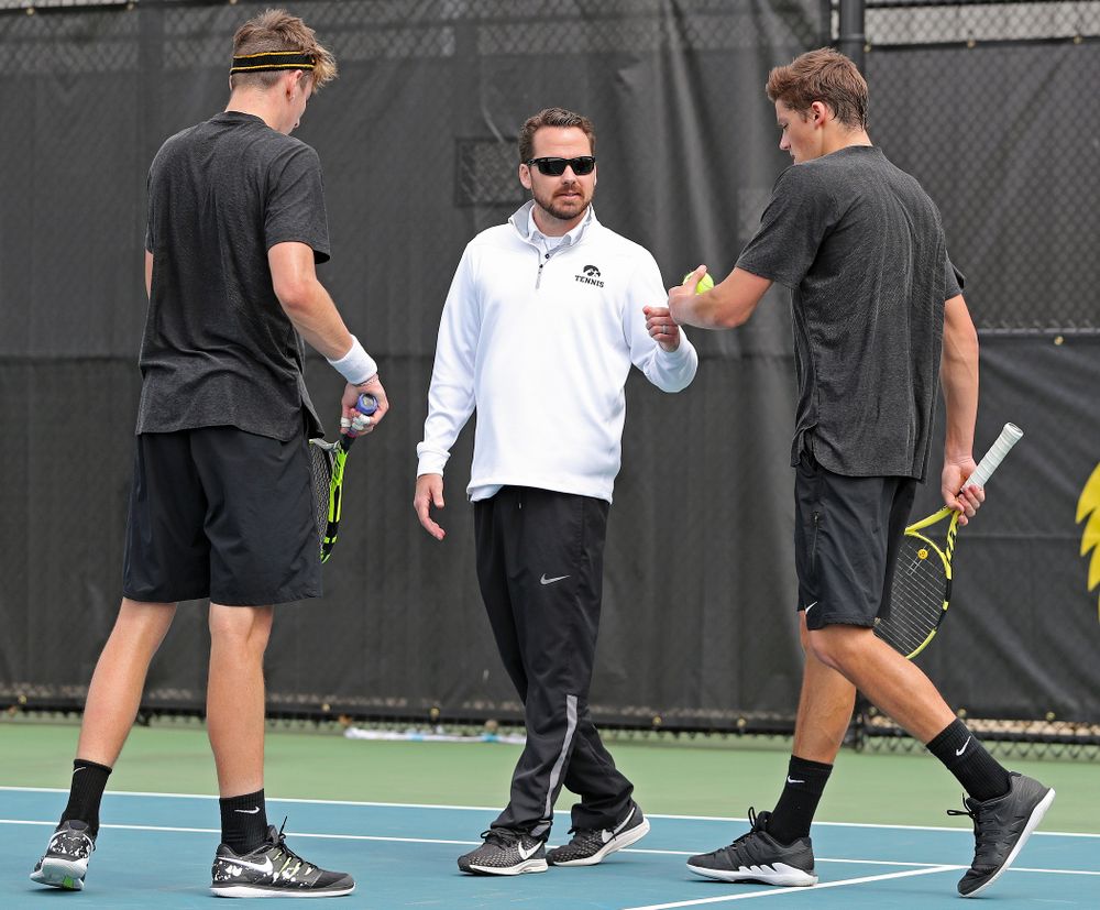 Iowa head coach Ross Wilson (center) talks with Nikita Snezhko (left) and Joe Tyler (right) during a double match against Ohio State at the Hawkeye Tennis and Recreation Complex in Iowa City on Sunday, Apr. 7, 2019. (Stephen Mally/hawkeyesports.com)