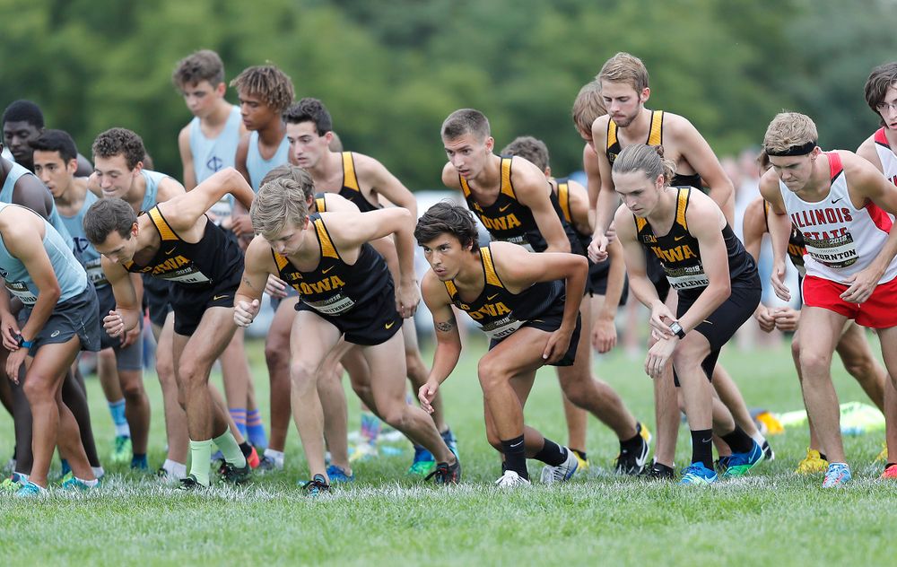 Cross country runners lean forward at the starting line