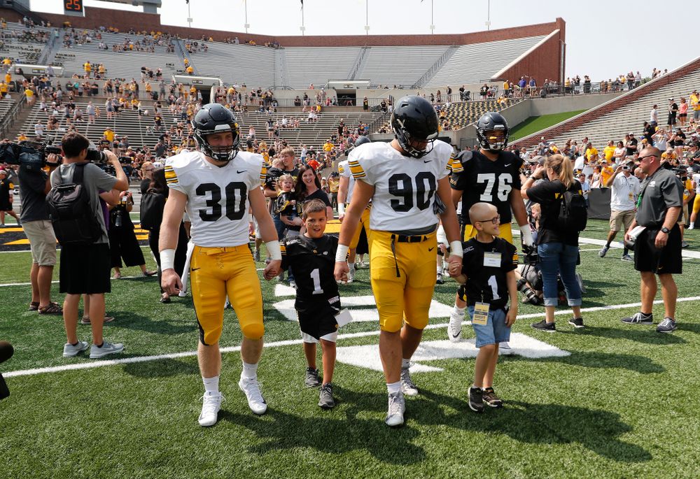 Iowa Hawkeyes defensive back Jake Gervase (30) and defensive end Sam Brincks (90) swarm with the Kid Captains during Kids Day Saturday, August 11, 2018 at Kinnick Stadium. (Brian Ray/hawkeyesports.com)