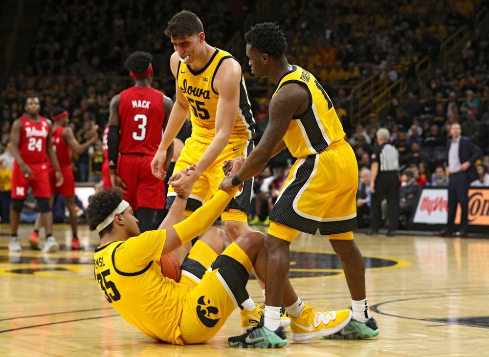 Iowa Hawkeyes center Luka Garza (55) and guard Joe Toussaint (1) help up forward Cordell Pemsl (35) after he was fouled during the first half of their game at Carver-Hawkeye Arena in Iowa City on Saturday, February 8, 2020. (Stephen Mally/hawkeyesports.com)