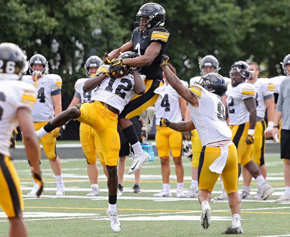 Iowa Hawkeyes defensive back D.J. Johnson (12) intercepts a pass intended for wide receiver Tyrone Tracy Jr. (3) as defensive back Geno Stone (9) closes in during Fall Camp Practice No. 11 at the Hansen Football Performance Center in Iowa City on Wednesday, Aug 14, 2019. (Stephen Mally/hawkeyesports.com)