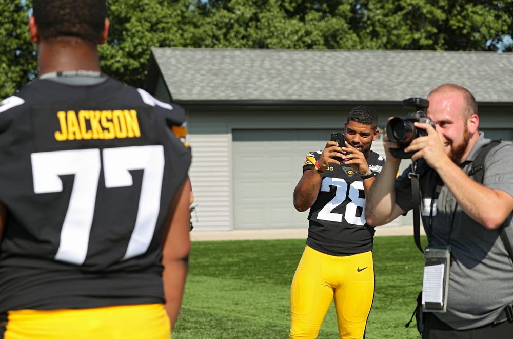 Iowa Hawkeyes running back Toren Young (28) takes a picture of offensive lineman Alaric Jackson (77) as he poses for a portrait during Iowa Football Media Day at the Hansen Football Performance Center in Iowa City on Friday, Aug 9, 2019. (Stephen Mally/hawkeyesports.com)