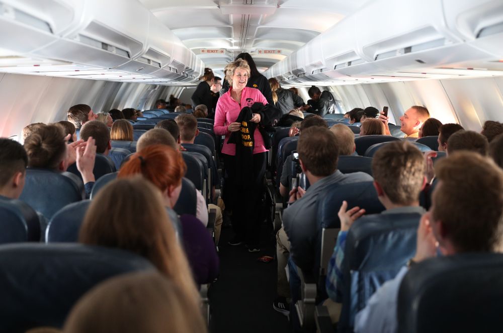 Iowa Hawkeyes head coach Lisa Bluder hands out t-shirts to the band and spirit squad on board the team plane to Greensboro, NC for the Regionals of the 2019 NCAA Women's Basketball Championships Thursday, March 28, 2019 at the Eastern Iowa Airport. (Brian Ray/hawkeyesports.com)