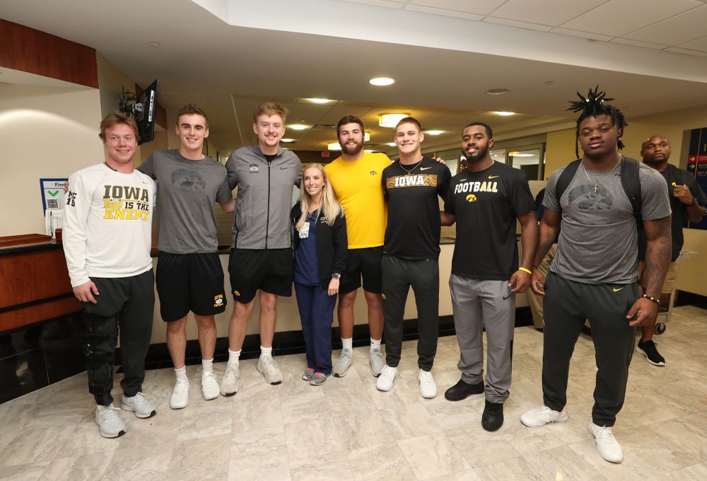 Iowa Hawkeyes tight end Ben Subbert (81), punter Ryan Gersonde (2), wide receiver Max Cooper (19), wide receiver Blair Brooks (83), quarterback Spencer Petras (7), linebacker Jayden McDonald (25), and defensive back Dallas Craddieth (15) pose for a photo with a nurse from Iowa during a visit to Tampa General Hospital as part of the Outback Bowl Friday, December 28, 2018 in Tampa, FL.(Brian Ray/hawkeyesports.com)