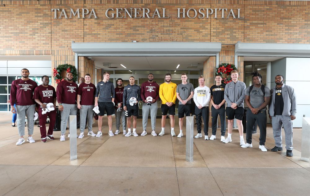 Iowa Hawkeyes tight end Ben Subbert (81), punter Ryan Gersonde (2), wide receiver Max Cooper (19), wide receiver Blair Brooks (83), quarterback Spencer Petras (7), linebacker Jayden McDonald (25), and defensive back Dallas Craddieth (15) pose for a photo with players from Mississippi State during a visit to Tampa General Hospital as part of the Outback Bowl Friday, December 28, 2018 in Tampa, FL.(Brian Ray/hawkeyesports.com)