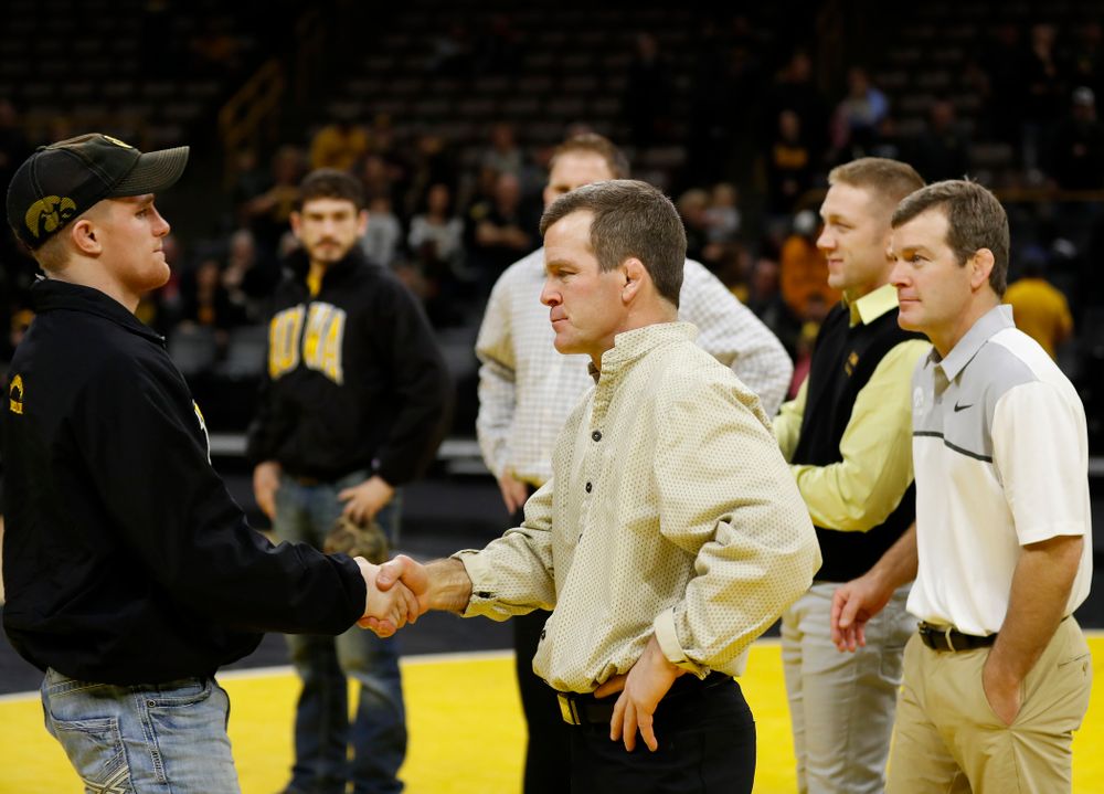 Iowa senior Phillip Laux shakes hands with associate head coach Terry Brands  following their meet against Northwestern