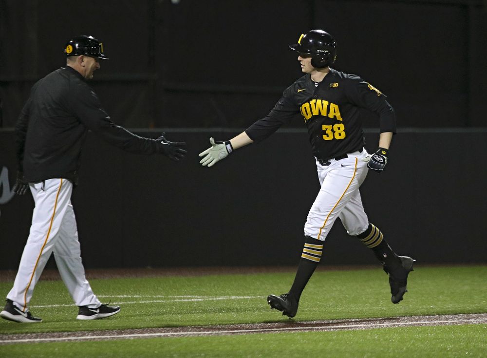 Iowa Hawkeyes head coach Rick Heller greets designated hitter Trenton Wallace (38) as he rounds the bases after hitting a home run during the eighth inning of their game at Duane Banks Field in Iowa City on Tuesday, March 3, 2020. (Stephen Mally/hawkeyesports.com)