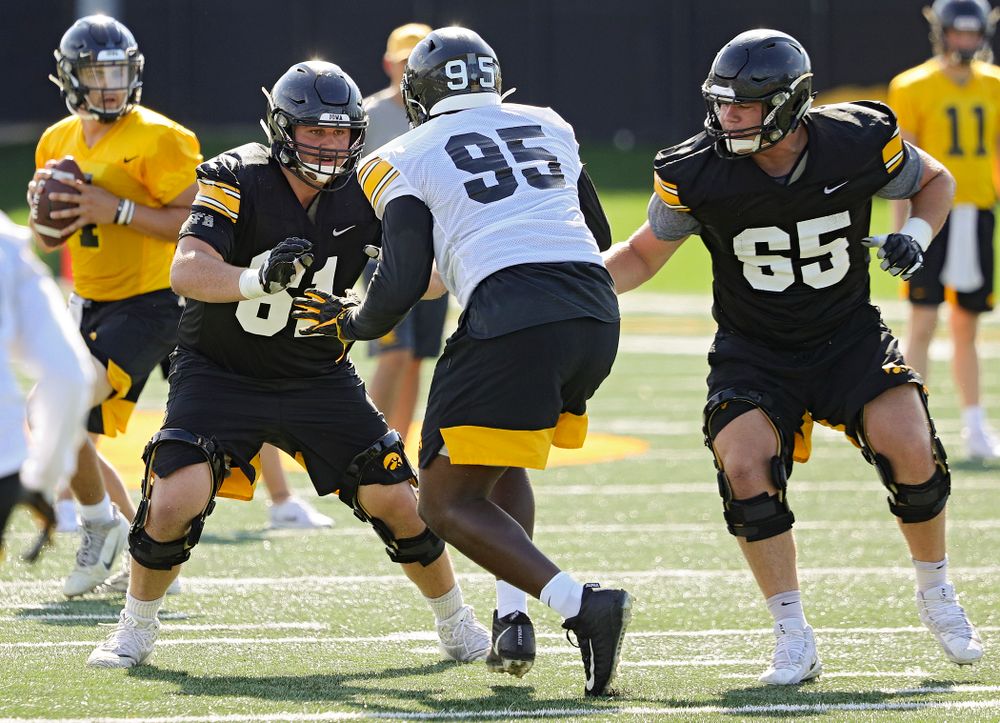 Iowa Hawkeyes offensive lineman Cole Banwart (61) and offensive lineman Tyler Linderbaum (65) eye defensive lineman Cedrick Lattimore (95) during Fall Camp Practice No. 13 at the Hansen Football Performance Center in Iowa City on Friday, Aug 16, 2019. (Stephen Mally/hawkeyesports.com)