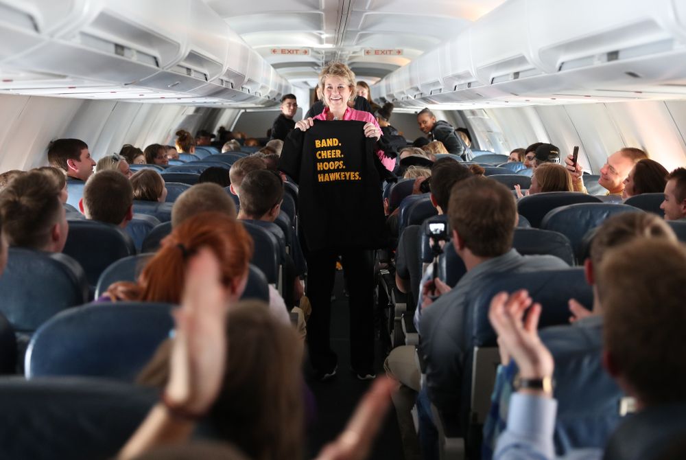 Iowa Hawkeyes head coach Lisa Bluder hands out t-shirts to the band and spirit squad on board the team plane to Greensboro, NC for the Regionals of the 2019 NCAA Women's Basketball Championships Thursday, March 28, 2019 at the Eastern Iowa Airport. (Brian Ray/hawkeyesports.com)