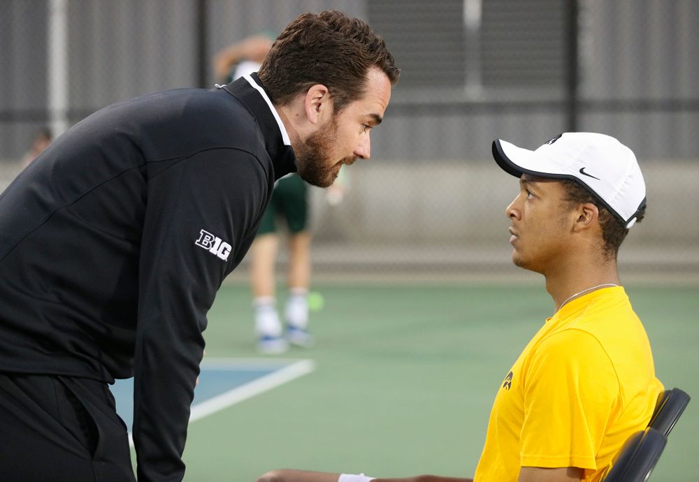 Iowa head coach Ross Wilson (from left) talks with Oliver Okonkwo during his match again Michigan State at the Hawkeye Tennis and Recreation Complex in Iowa City on Friday, Apr. 19, 2019. (Stephen Mally/hawkeyesports.com)