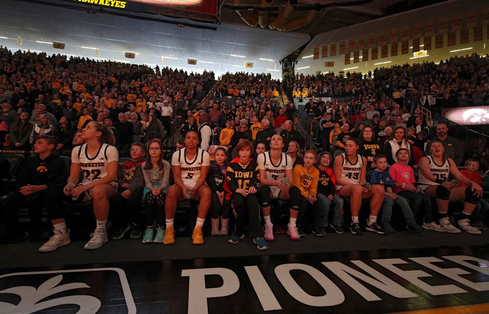 Iowa Hawkeyes guard Kathleen Doyle (22), guard Alexis Sevillian (5), guard Makenzie Meyer (3), forward Amanda Ollinger (43), and forward Monika Czinano (25) sit on the bench with Go Red for Women Movement Heart Champions before being introduced at the start of their game at Carver-Hawkeye Arena in Iowa City on Sunday, January 26, 2020. (Stephen Mally/hawkeyesports.com)