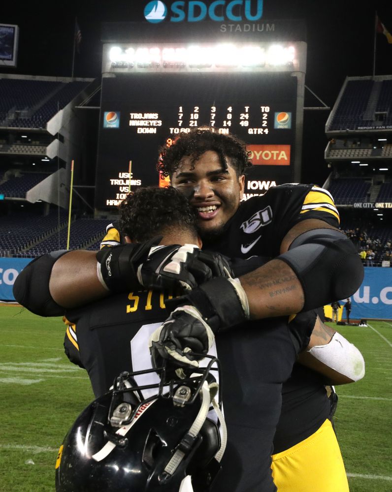 Iowa Hawkeyes offensive lineman Tristan Wirfs (74) hugs defensive back Geno Stone (9) after their win against USC in the Holiday Bowl Friday, December 27, 2019 at San Diego Community Credit Union Stadium.  (Brian Ray/hawkeyesports.com)