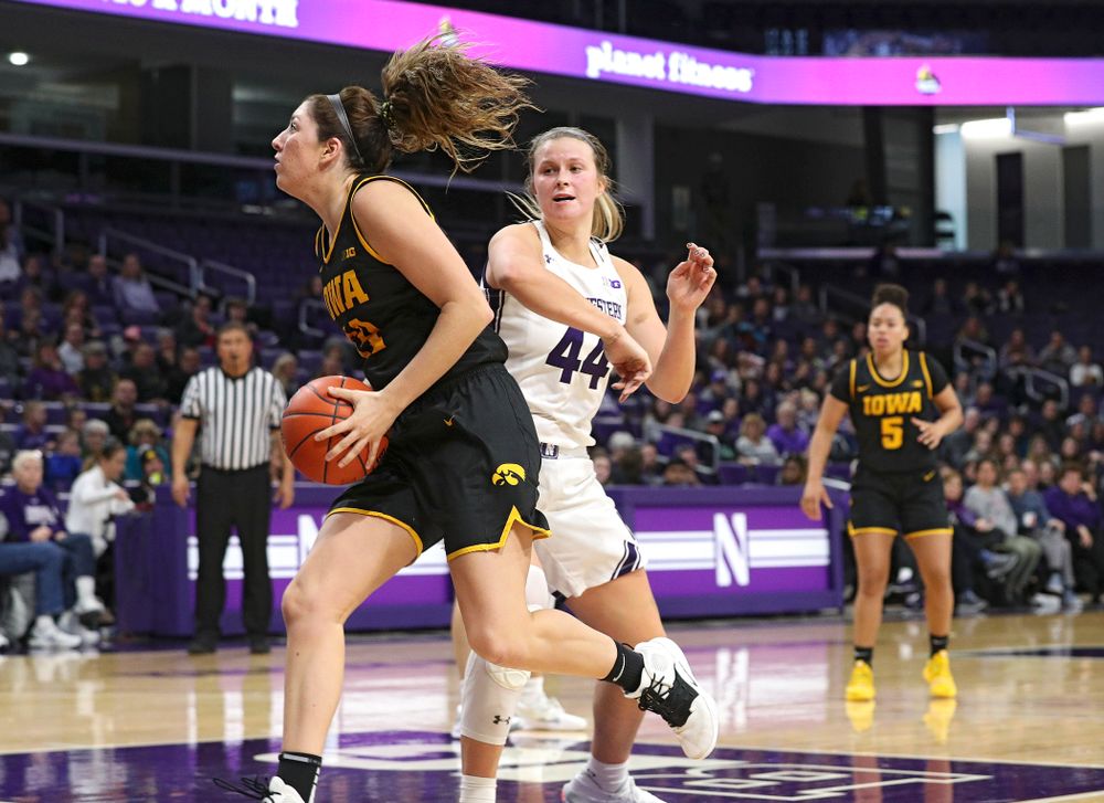 Iowa Hawkeyes guard Mckenna Warnock (14) spins away from Northwestern Wildcats forward Abi Scheid (44) before scoring a basket during the fourth quarter of their game at Welsh-Ryan Arena in Evanston, Ill. on Sunday, January 5, 2020. (Stephen Mally/hawkeyesports.com)